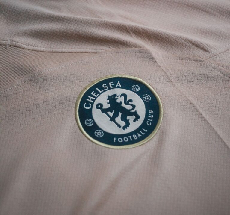 Close-up view of Chelsea Football Club logo on a beige t-shirt, ideal for sports and fashion themes.