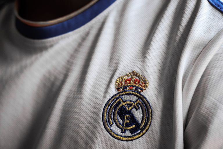 Detailed close-up of a soccer jersey featuring a prominent emblem on white fabric.